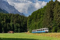 Zwischen Grainau und Eibsee  Direkt hinter dem Bahnhof Grainau geht es für die schmalspurigen Zahnrad-Züge der Bayerischen Zugspitzbahn bereits in eine beachtliche Steigung, um den Anstieg zum rund drei Kilometer entfernten Eibsee zu schaffen. Triebwagen 12, gebaut 2006 von Stadler, rollt hier bereits durch die Wiesen unterhalb des Bergmassivs. Die Steigung kann man auf diesem Foto bestenfalls erahnen (6. Juli 2022). Am Bergmassiv kann man noch eine der Stützen für die Seilbahn vom Eibsee zur Zugspitze erkennen. : a Deutschland, eb BZB ET 12, ef L4122/1 Stadler (2006)