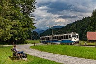 Talfahrt nach Grainau  Zurück an der Zugspitzbahn, nur wenige hundert Meter von dem Motiv zwei Bilder zuvor entfernt. Diesmal sehen wir den Triebwagen 15 auf der Fahrt vom Bahnhof Eibsee nach Grainau. Während die Fahrt zunächst entlang der Straße und durch Wald verlief, rollt der Zug nun ab der Christhütte über eine breite Lichtung. Über einen Wanderweg lassen sich die Zugfahrten hervorragend beobachten (10. Juli 2022). : BZB - Bayrische Zugspitzbahn, a Deutschland, ao Grainau, ao Grainau-Eibsee, eb BZB ET 15