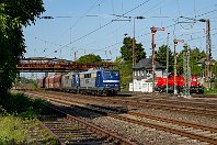 km 20,6  In Düsseldorf-Rath überspannt eine ältere Eisenträgerbrücke die Bahnanlagen. Während sich die Rangierlok 261 108-5 am Stellwerk Rn ausruht, rollt ein schwerer Ganzzug mit den RBH-Loks 265 und 266 in Doppeltraktion (ehemalige DB-Loks 151 084-1 und 151 024-7) Richtung Süden. Auf den beiden linken Gleisen fädelt hier die Ruhrtalbahn (Strecke 2400) ein, die südlich des Bahnhofs Rath wieder die gemeinsame Trasse verlässt (7. August 2015). : 91 80 6151, RAG / RBH Logistics GmbH, a - Aufnahmeort, a Deutschland, ao Düsseldorf, ao Düsseldorf-Rath, eb RBH 265, eb RBH 266, ef 5334 Krupp, en 91 80 6151 024, en 91 80 6151 084-1, es 2324 km 20-6