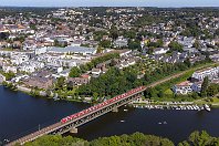 km 19,7  Und noch eine Aufnahme aus luftiger Höhe auf Essen-Kettwig und die Ruhrbrücke. Am 14. August 2021 heult hier eine Doppeleinheit 422 über die aufgestaute Ruhr und wird nach nur noch wenigen Metern am Haltepunkt »Kettwig Stausee« zum Halten kommen. Der Blick geht weit zum Horizont: Ganz links oben ist der bekannte Gasometer in Oberhausen zu sehen, etwas weiter rechts die schon auf Bottroper Stadtgebiet liegende Halde Haniel. : 422 / 432", a Deutschland, ao Essen, ao Essen-Kettwig, eb DB 422 xxx, ei - Eisenbahn-Infrastruktur, ei Brücke Ruhr