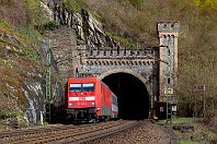 km 126,2  Südlich von St. Goar wird die Linke Rheinstrecke durch drei Tunnel geführt. Der erste ist der 367 Meter lange Banktunnel, dessen Türmchen die Rheinromantik widerspiegelt. 101 145-1, die letztgebaute Lok ihres Typs mit der Fabriknummer 33333, verlässt hier mit dem IC 119 den Tunnel und rollt weiter Richtung Mainz. Das Schild rechts im Bild kündigt den Regionalzügen den nächsten Halt an (2. April 2016). : 101, 2, 91 80 6101, Str 2630 K - KO - Bingen Hbf "Linke Rheinstr", Tunnel, a - Aufnahmeort, a Deutschland, ao St. Goar, ao St. Goar Bank-Tunnel, eb DB 101 145-1, ef 33333 ADtranz Ksl (1999), ei - Eisenbahn-Infrastruktur, en 91 80 6101 145-1, es 2630 km 126-2, ez - Zugnummer, ez IC 119