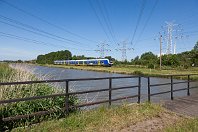 km 37,4  Fast gleiche Fotostelle, mit etwas anderem Blickwinkel: Die Strecke verläuft hier am Kernkraftwerk Unterweser vorbei, dessen gewaltige Kuppel hier noch knapp über den Baumwipfeln zu sehen ist. Es war von 1978 bis 2011 in Betrieb. Ob die Hochspannungsleitungen auch über das Ende des KKW hinaus Bestand haben, ist mir leider nicht bekannt. Hier rauscht ET 440 211 der NWB an der Anlage vorbei (3. Juni 2011). : 94 80 0440 (CContinental), NWB - Nordwestbahn, Str 1503 Hude - Blexen, a - Aufnahmeort, a Deutschland, ao Kleinensiel, eb NWB ET 440 211, en 94 80 0440 711-0, es 1503 km 37-4, neue Nr