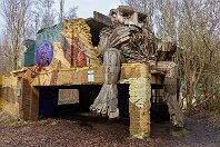 049 Hannes  »Hannes« gehört zu sieben Trollen, die 2019 im belgischen Naherholungsgebiet »De Schorre« bei Boom aufgebaut wurden. Das ungefähr 75 Hektar große Gebiet war früher eine Tongrube mit Ziegeleien, einige Gebäude aus dieser Zeit stehen immer noch.  Der Troll sitzt auf den alten Gemäuern und zieht Perlen auf eine Kette. Fotos vom 10. Februar 2024. : K Thomas Dambo, Troll 049 - Hannes, a Belgien, ao Boom